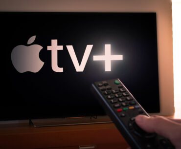 Handing holding a remote in front of an Apple TV with VPN