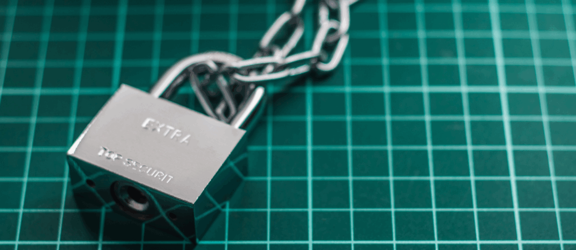 A metal lock with the word "Extra" written on it is attached to a metal chain on a green field with white lattices.