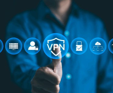 A man with a blue buttondown shirt is blurry in the background. He is holding up a thumbs up, with the thumb also pressing a circle on the screen that reads "VPN". There are three other circles on each side representing secure Chrome extensions.