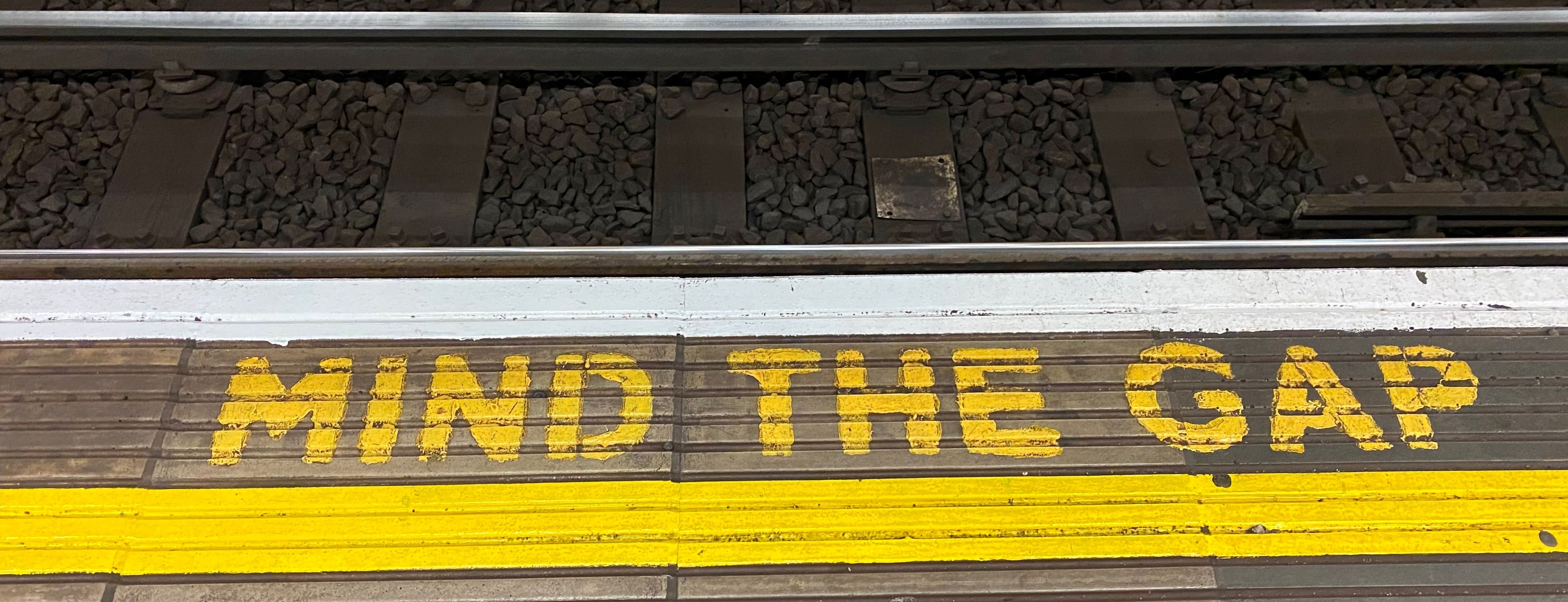 Picture of a spray-painted train platform that reads, "Mind the gap."