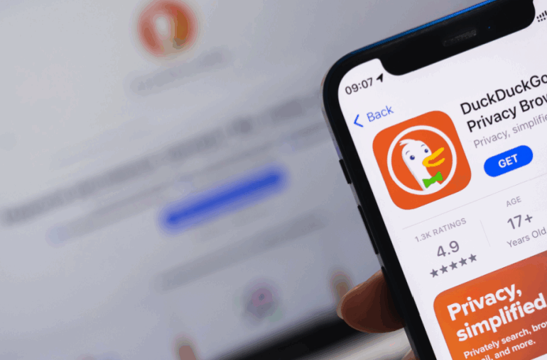 A cellphone has the DuckDuckGo app on the screen in front of a laptop with DuckDuckGo on it. It implies an answer to the questions, "Is DuckDuckGo safe?"