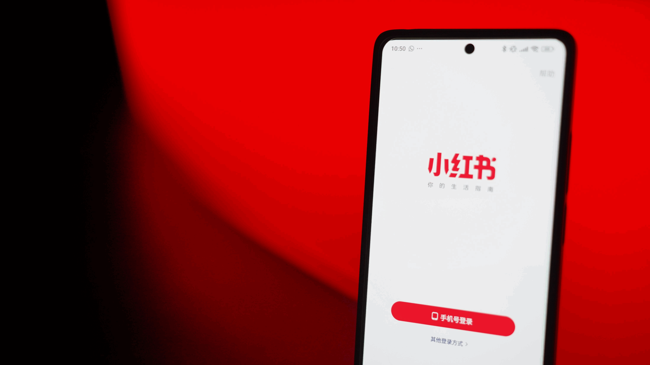 Image of the RedNote app on a cellphone in front of a red and black background.