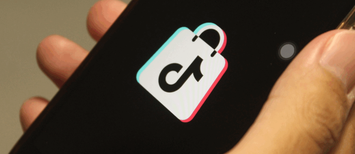 Hand holding a cellphone with the TikTok Shop logo on it.