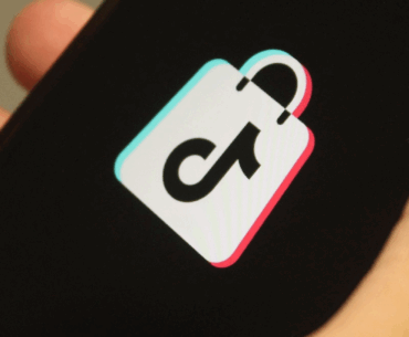 Hand holding a cellphone with the TikTok Shop logo on it.