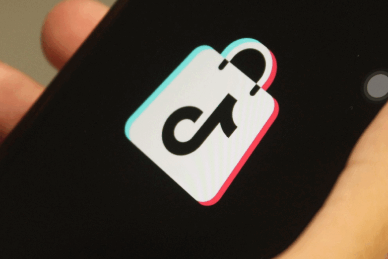 Hand holding a cellphone with the TikTok Shop logo on it.