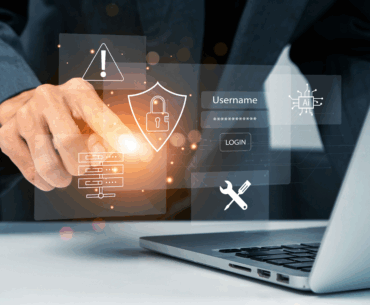 A hand is reaching out and touching a hologram of a shield with a lock on it that is hovering with other icons above a laptop's keyboard. These representing using the best vpn and antivirus.