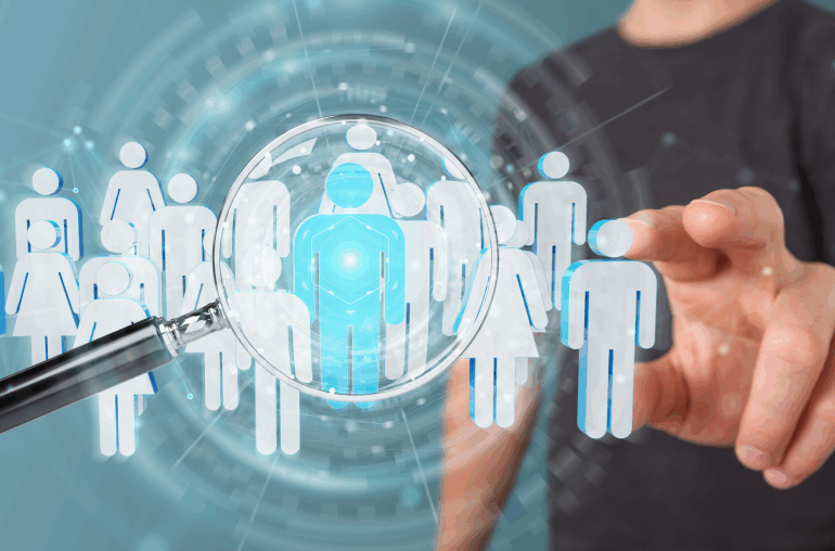 A man in a black t-shirt is reaching out toward the screen. There are several icons of people hovering in front of him. One of the icons is blue and being looked at through a magnifying glass.