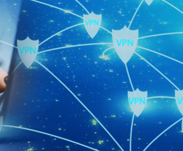 Closeup of a person's hand with black nail polish typing on a laptop. The back of the laptop fades into a star field with a bunch of shields, each emblazoned with "VPN", scattered on it. The shields are connected by lines, representing the Smart locations feature.